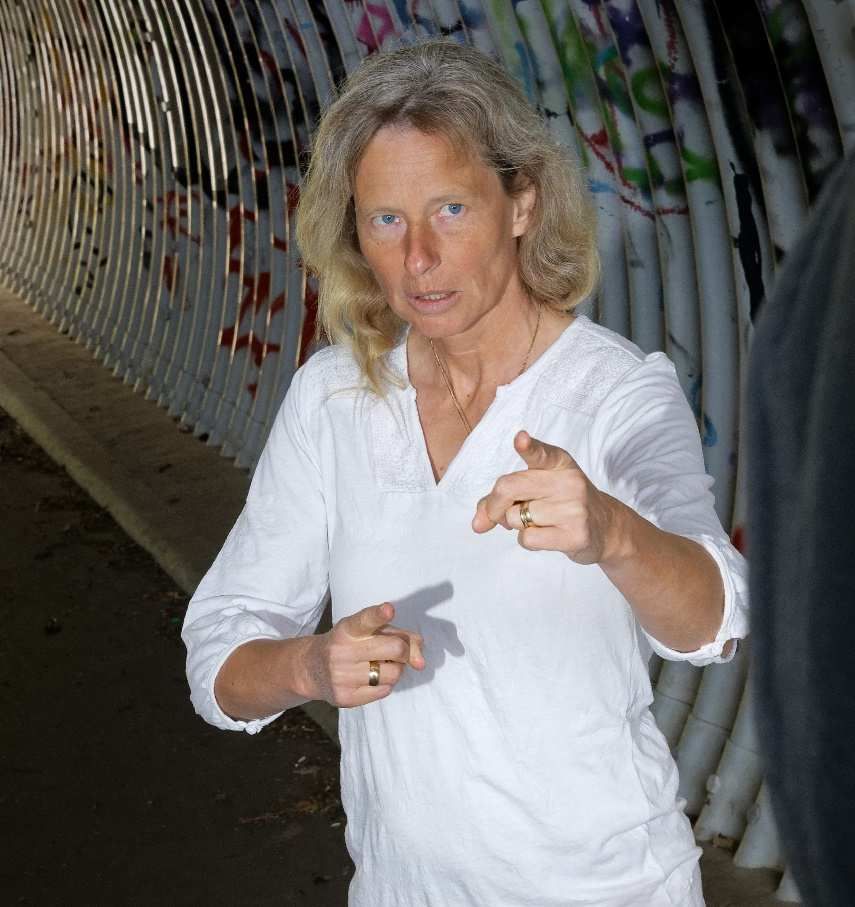 Trainerin zeigt mit beiden Händen auf die Kamera